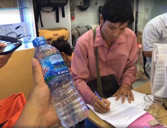 Khách hàng yêu cầu nhân viên GHN lập biên bản xác nhận việc máy ảnh bị tráo đổi thành chai nước lọc. Ảnh: Chu Bình. 